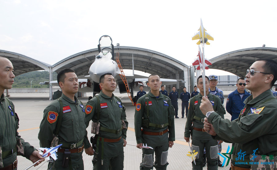 ↑艦載航空兵某部司令員戴明盟向飛行員演示空中飛行注意事項(xiàng)。