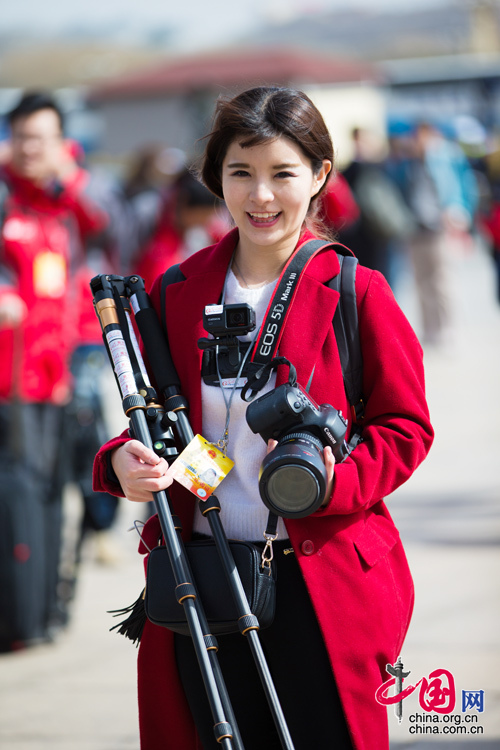 2016年兩會(huì)，人民大會(huì)大堂前，一位笑容燦爛的紅衣女記者正步入大會(huì)堂。中國(guó)網(wǎng) 鄭亮 攝