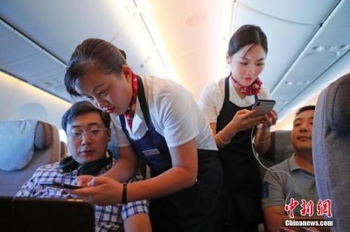 資料圖：乘務員們在客艙內(nèi)為旅客調(diào)試機上上網(wǎng)功能。<a target='_blank' ><p  align=